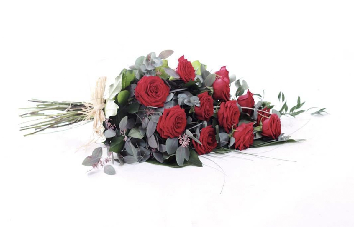 Bouquet of red roses with greenery tied with twine on a white background